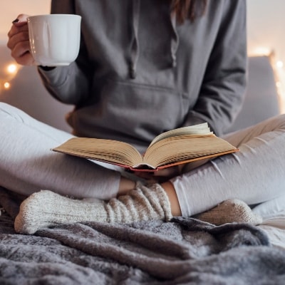 Девушка читает книгу холодной осенью в тёплых носках