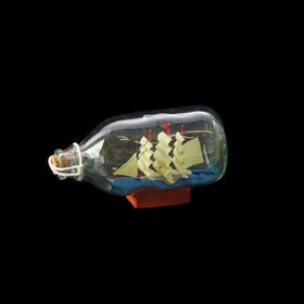 Souvenir ship in a bottle with white sails striped